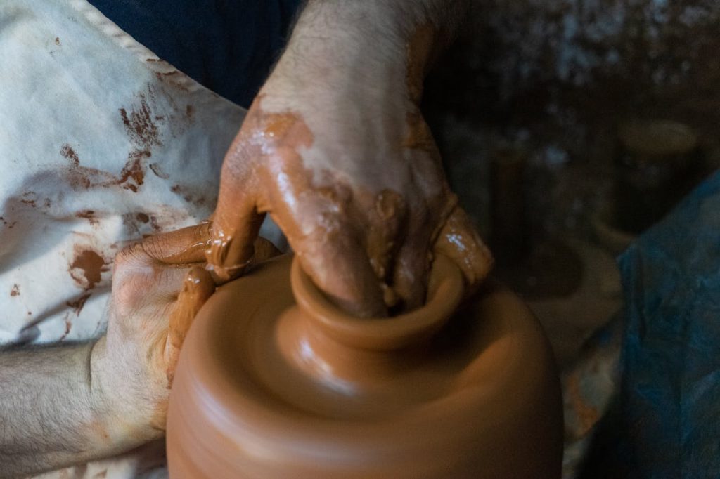 close-up-of-potter-shaping-clay-on-pottery-wheel-34259428